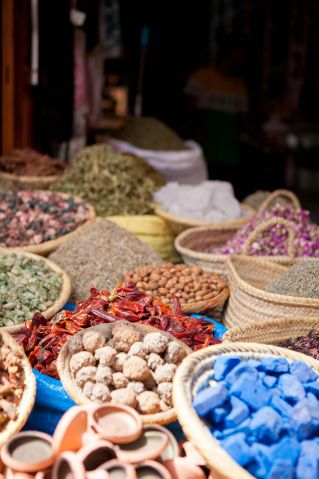 A vibrant display of assorted spices and goods at a market stall in Marrakech, Morocco.